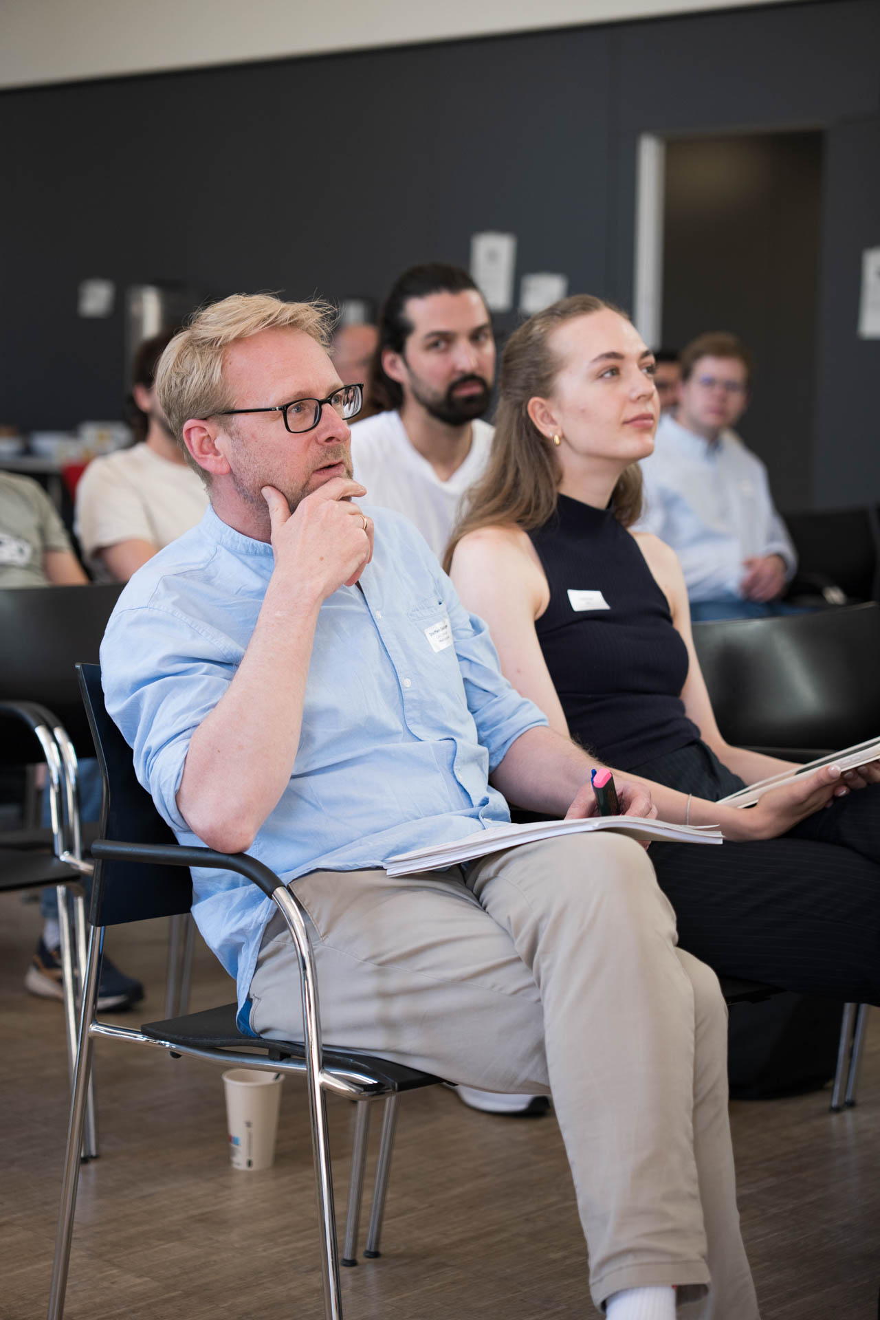Zwei Personen sitzen in der ersten Reihe im Publikum der Veranstaltung
